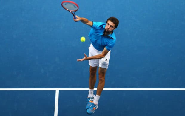 A tennis player is serving the ball during a match on a blue court, HD Desktop Wallpaper