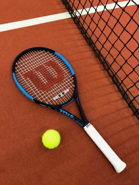 A tennis racket and ball rest near the net on a clay court surface representing tennis wallpapers, HD Mobile Wallpaper