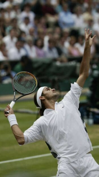 A tennis player prepares to serve during a match on a grass court, HD Mobile Wallpaper