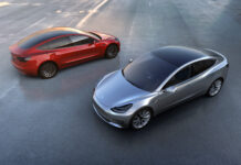 Two Tesla Model 3 cars in silver and red colors parked on an empty lot during daytime, 2K Desktop Wallpaper