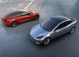 Two Tesla Model 3 cars in silver and red colors parked on an empty lot during daytime, 2K Desktop Wallpaper