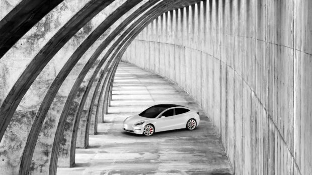 Tesla Model 3 is parked under a curved concrete structure showcasing modern design, 4K Desktop Wallpaper