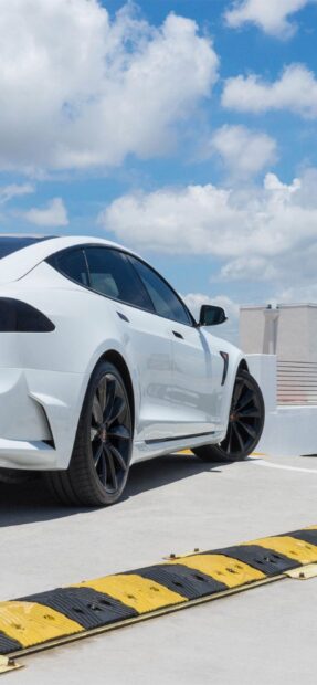 A white Tesla Model 3 is parked in a sunny outdoor location with blue skies and clouds, 2K Mobile Wallpaper