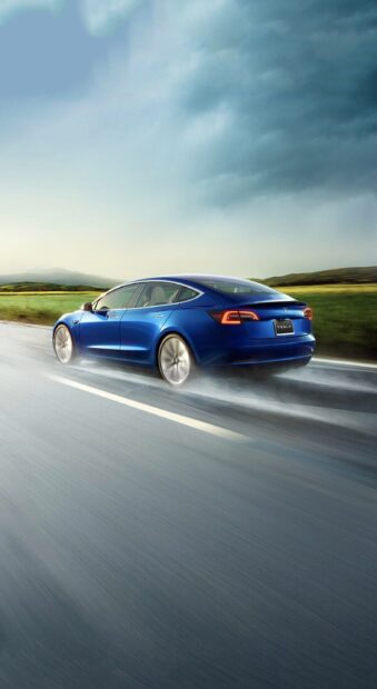 A blue Tesla Model 3 is driving fast on a wet road with a cloudy sky, 2K Phone Wallpaper
