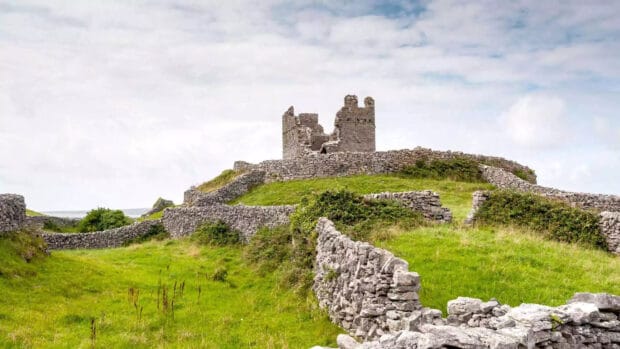The Aran Islands show a historic stone castle surrounded by green fields and cloudy sky, HD Desktop Wallpaper