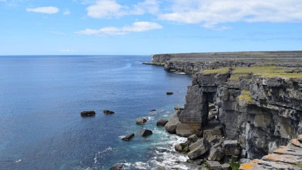 The Aran Islands show rocky cliffs meeting the blue ocean under a clear sky, HD Desktop Wallpaper
