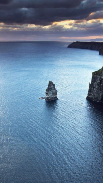 A rocky sea stack near the Aran Islands contrasts with the calm blue ocean under a cloudy sky, HD Phone Wallpaper