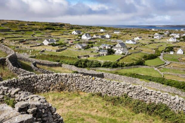The Aran Islands show stone walls and houses with green fields under a cloudy sky, HD Desktop Wallpaper