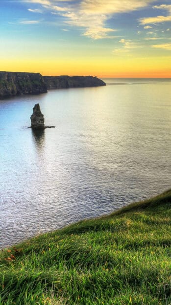 The Aran Islands feature a peaceful coastline with rocky cliffs and calm seas at sunset, HD Phone Wallpaper