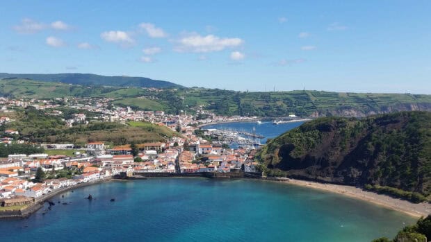 The Azores Wallpapers show a scenic coastal town with green hills and blue water under a clear sky, HD Desktop Wallpaper
