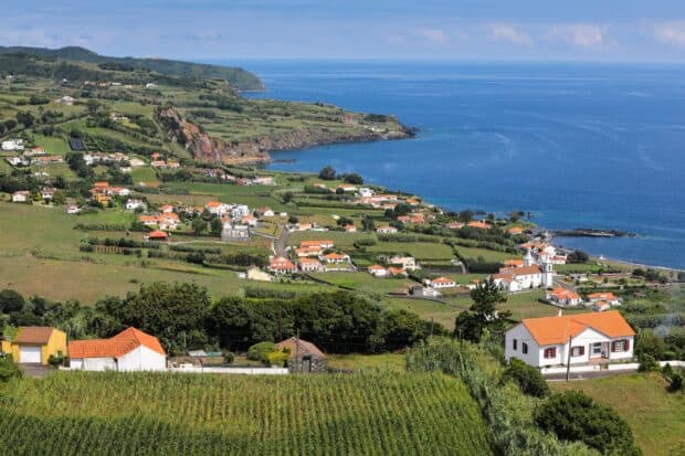 A scenic coastal view of The Azores with green fields and houses by the ocean, HD Desktop Wallpaper