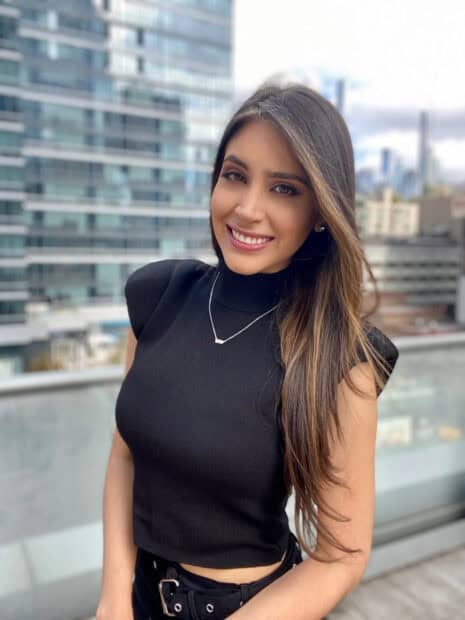 A woman in a black top poses smiling with city buildings behind her in The Bachelor TV Series, HD Mobile Wallpaper