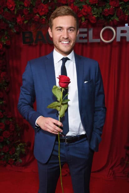 A man in a blue suit holding a single red rose at The Bachelor event, HD Mobile Wallpaper