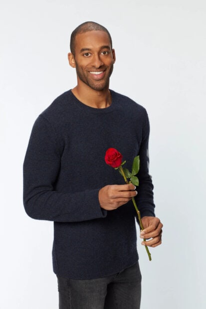A man from The Bachelor Tv Series is holding a red rose and smiling, 2K Portrait Mobile Wallpaper