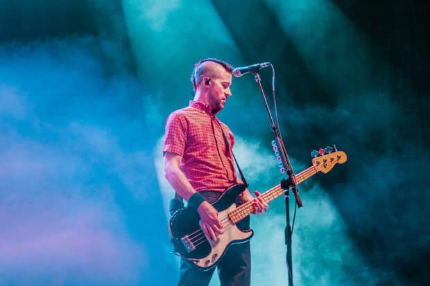 A band member from The Interrupters is playing bass guitar on stage during a concert, HD Desktop Wallpaper