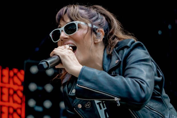 The Interrupters lead vocalist singing passionately during a live concert, HD Desktop Wallpaper