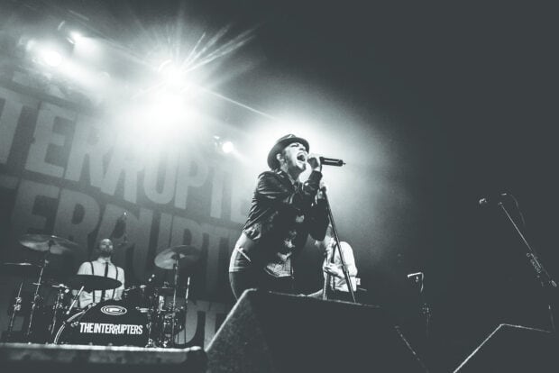 The Interrupters band performing live on stage with energetic vocals, HD Desktop Wallpaper
