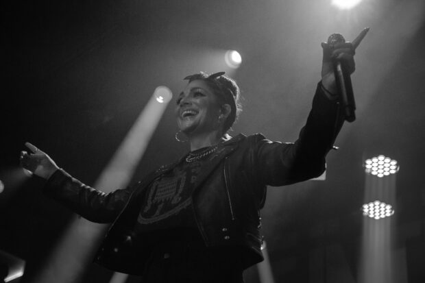 A member of The Interrupters smiles while performing on stage with a microphone, HD Desktop Wallpaper