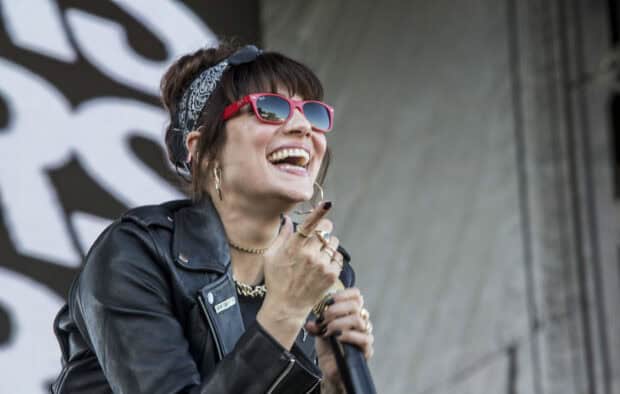 A member of The Interrupters smiles while singing on stage during a concert, HD Desktop Wallpaper