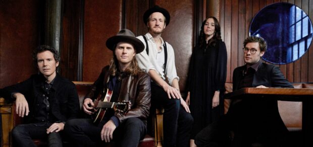 The Lumineers group is sitting in a vintage room with musical instruments and thoughtful expressions, 2K Desktop Wallpaper