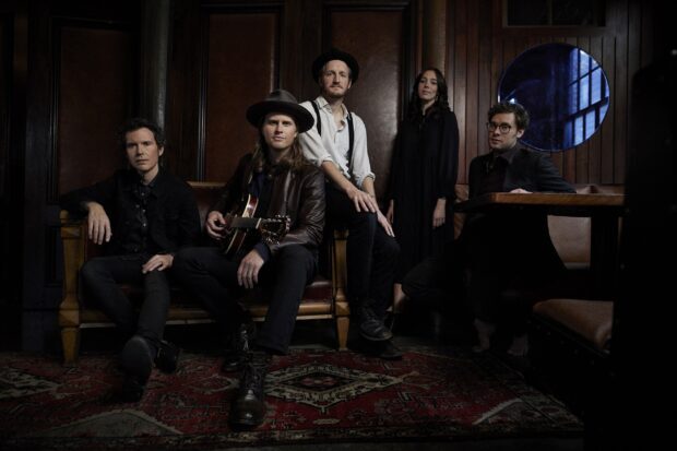 The Lumineers Wallpapers shows the band members seated in a room with wooden walls and a vintage rug, 2K Desktop Wallpaper