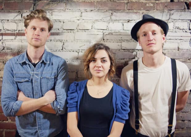 The Lumineers pose in front of a brick wall with casual clothing and serious expressions, 2K Desktop Wallpaper