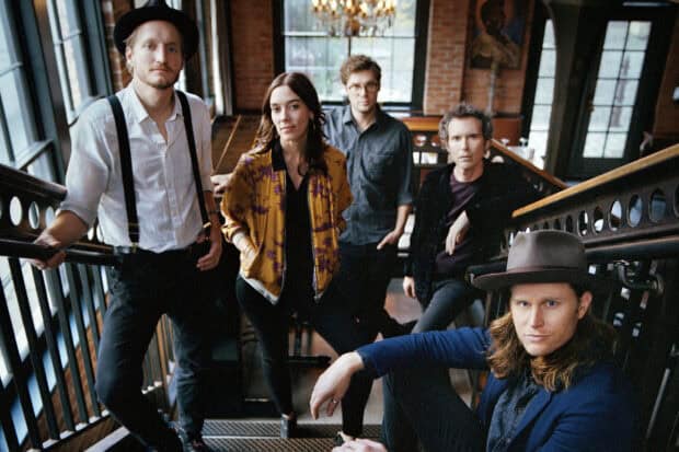 The Lumineers band members stand on a staircase inside a rustic building, HD Desktop Wallpaper