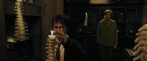 Harry Potter lights a candle in a dark room with objects behind him, 4K Desktop Wallpaper