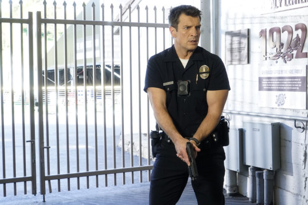 A police officer holding a gun stands alert near a gate in The Rookie TV series, 2K Desktop Wallpaper
