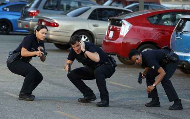Three police officers are cautiously holding guns and taking cover in a parking lot, HD Desktop Wallpaper