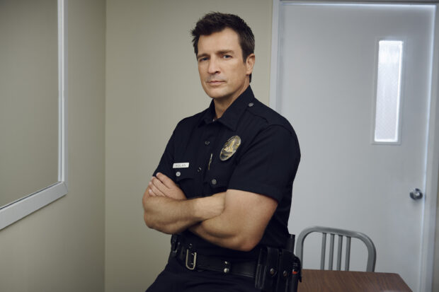 A police officer in uniform poses with arms crossed in an interrogation room from The Rookie Tv Series, 2K Desktop Wallpaper