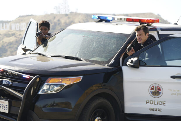 Two police officers aim their guns outside a patrol car in a tense moment, 2K Desktop Wallpaper