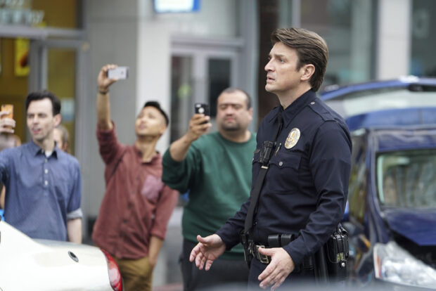 A police officer in uniform stands amidst bystanders using phones, 2K Desktop Wallpaper