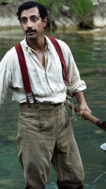 A man wearing suspenders stands in water holding a wooden stick in The Sisters Brothers, HD Phone Wallpaper