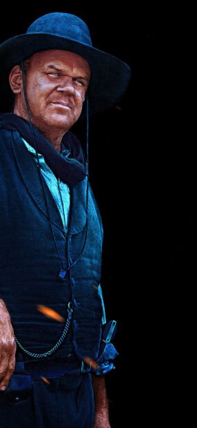 A man wearing a wide brimmed hat from The Sisters Brothers stands in a dark background, HD Phone Wallpaper
