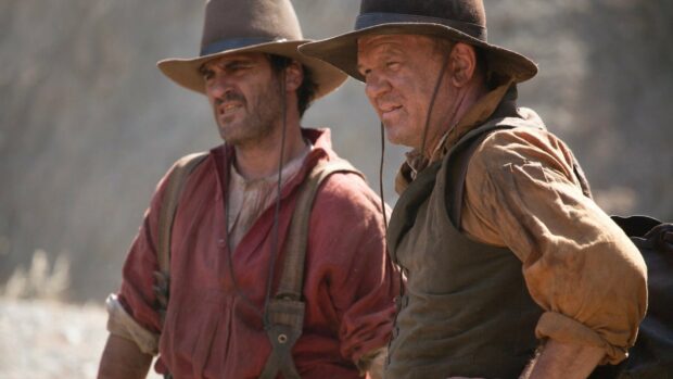 Two rugged men wearing hats stand outdoors in a tense moment, HD Desktop Wallpaper