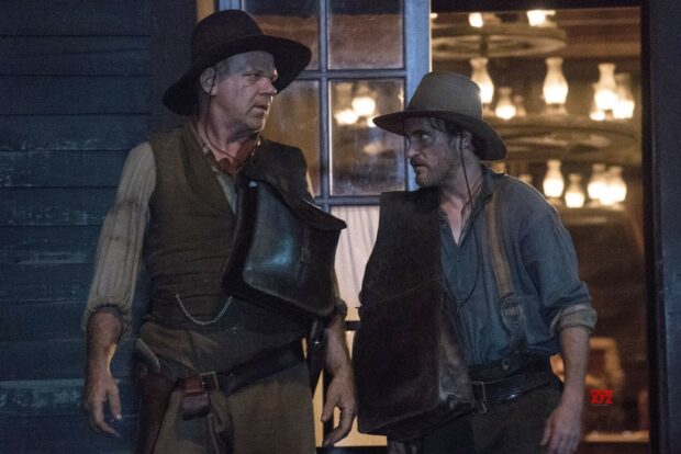 The Sisters Brothers stand outside a building wearing hats and vests in a tense scene, 2K Desktop Wallpaper