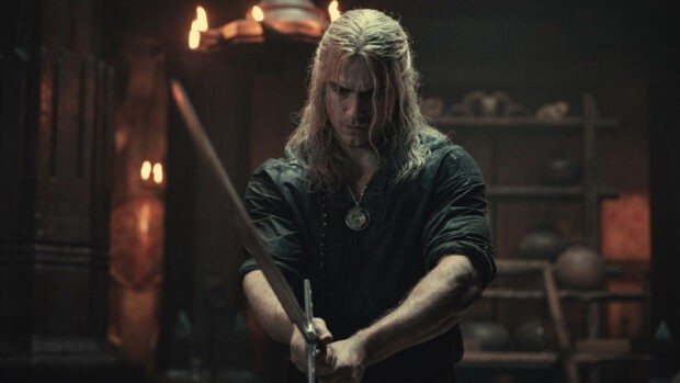 The Witcher is holding a sword in a dimly lit room, HD Desktop Wallpaper