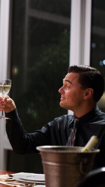 A man from The Wolf Of Wall Street raises a glass during a dinner scene, HD Phone Wallpaper
