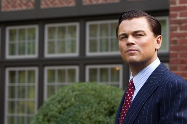 A serious man in a suit stands outdoors near a windowed building representing The Wolf Of Wall Street, 2K Desktop Wallpaper
