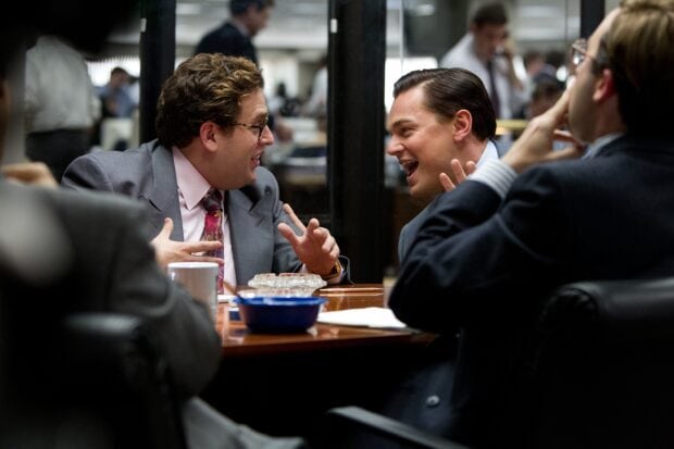 Two men are engaged in an animated conversation during a busy office setting, 2K Desktop Wallpaper