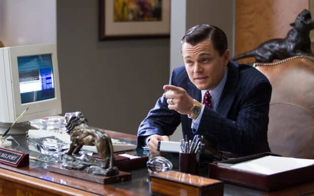 A man in a suit is sitting at an office desk with a computer and lion statue, 2K Desktop Wallpaper