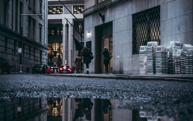 Two people walk down a city street with tall buildings and car lights, 2K Desktop Wallpaper