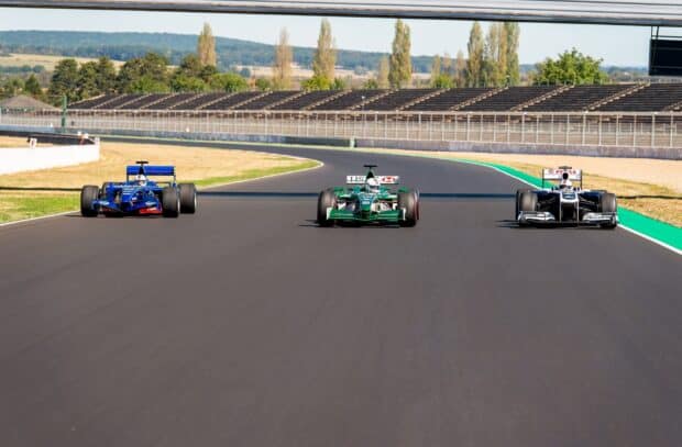 Three F1 race cars are competing closely on a sunny race track, HD Desktop Wallpaper