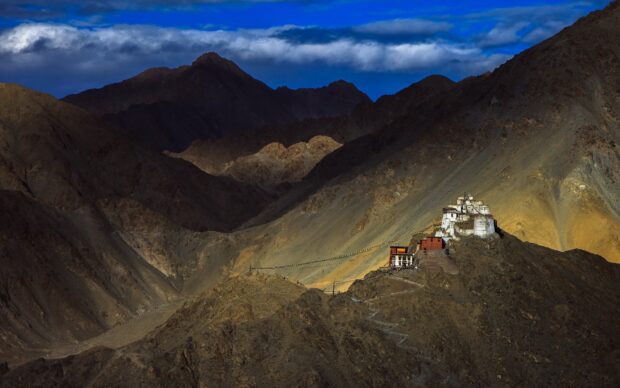 A mountain monastery stands illuminated in the rugged Tibetan Highlands landscape, HD Desktop Wallpaper