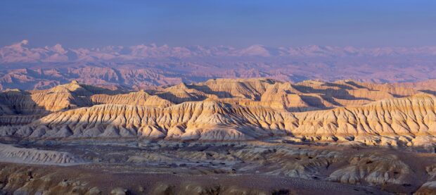 The Tibetan Highlands display layered ridges and snow capped peaks under a clear sky, 2K Desktop Wallpaper