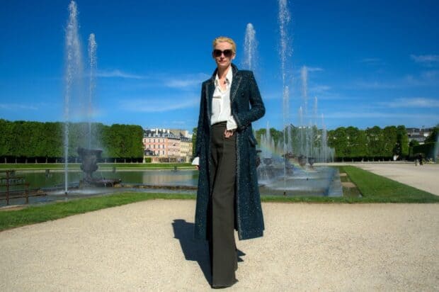 Tilda Swinton is standing confidently in front of a fountain under a clear blue sky, HD Desktop Wallpaper