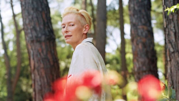 Tilda Swinton is standing in a forest with blurred flowers in the foreground, HD Desktop Wallpaper
