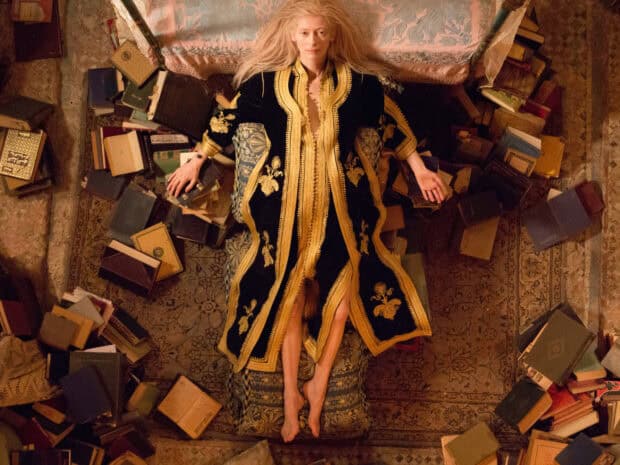 Tilda Swinton lies surrounded by scattered books wearing an ornate robe, HD Desktop Wallpaper
