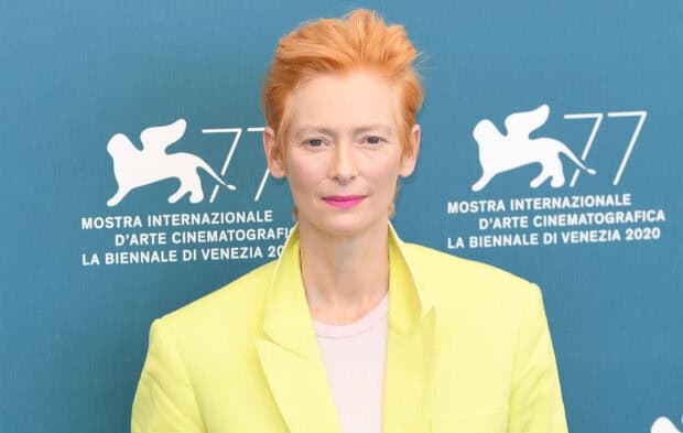 Tilda Swinton stands confidently with short orange hair and bright attire, HD Desktop Wallpaper